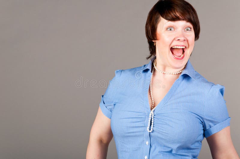 Caucasian business woman is loudly screaming, on gray background