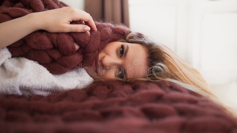 Loura jovem e bonita deitada na cama envolta num cobertor confortável e confortável Calor e conforto da casa