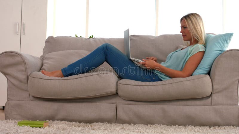 Loira feliz com portátil no sofá video estoque