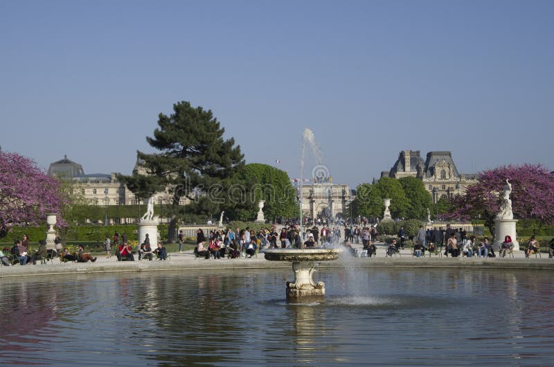 Beautiful fountain in park des tuileries with many people siting and relaxing in the sun. Beautiful fountain in park des tuileries with many people siting and relaxing in the sun.