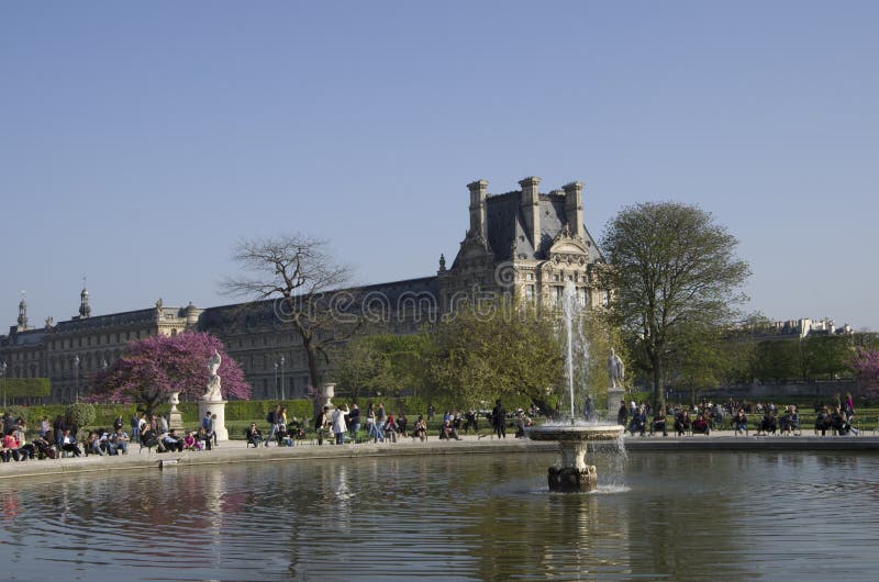 Beautiful fountain in park des tuileries with many people siting and relaxing in the sun. Beautiful fountain in park des tuileries with many people siting and relaxing in the sun.