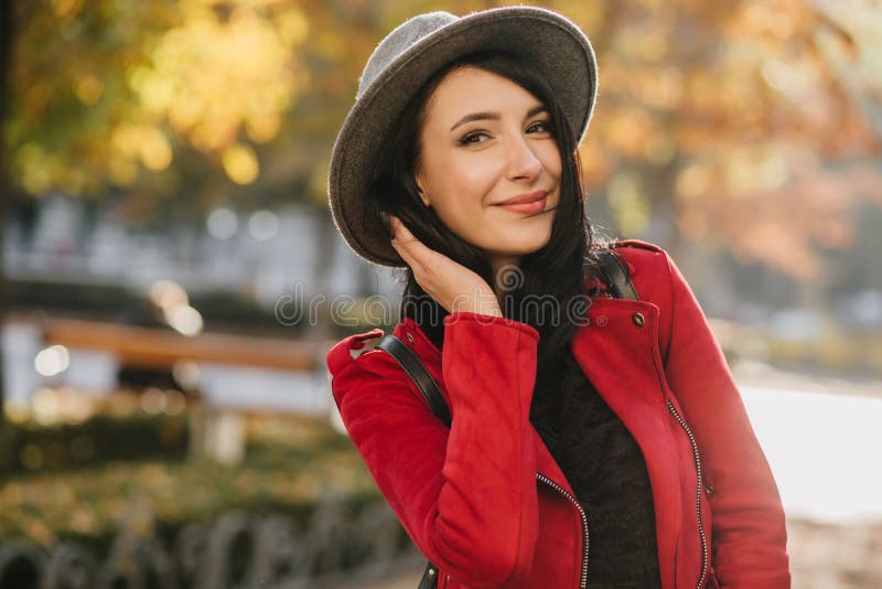 Lovable brunette woman in elegant gray hat posing on blur nature background. Positive dark-haired girl in bright jacket royalty free stock photos Lovable brunette woman in elegant gray hat posing on blur nature background. Positive dark-haired girl in bright jacket royalty free stock photos