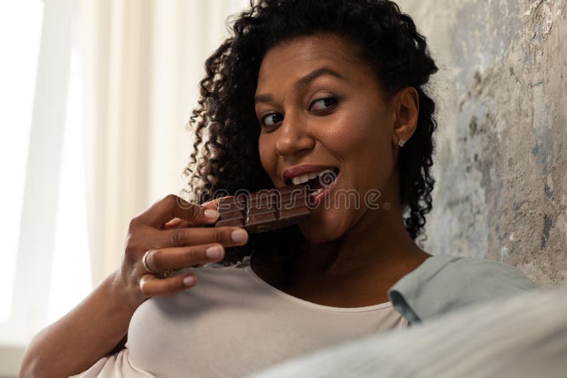 Pretty woman eating a chocolate bar and smiling. royalty free stock images Pretty woman eating a chocolate bar and smiling. royalty free stock images