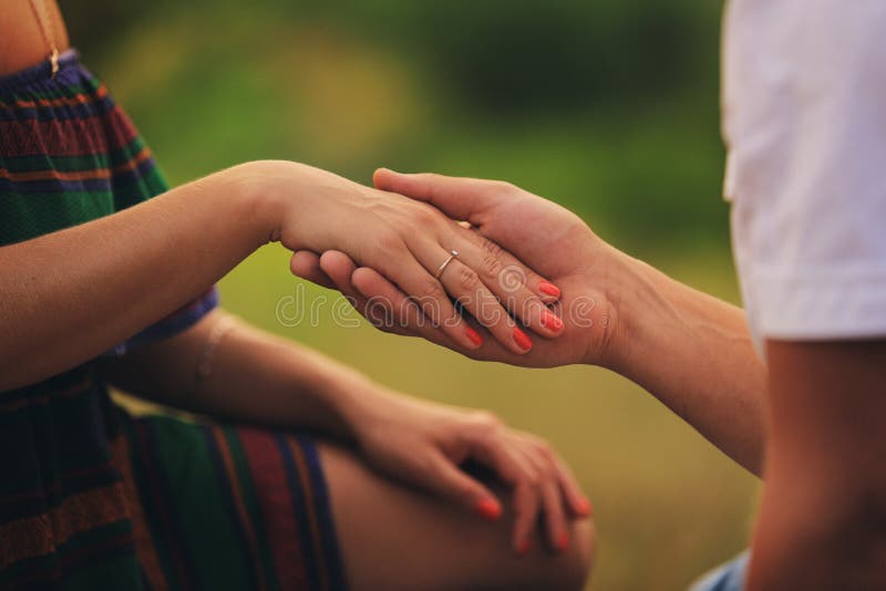 Hands of a young couple with a ring. close up of man giving diamond ring to woman