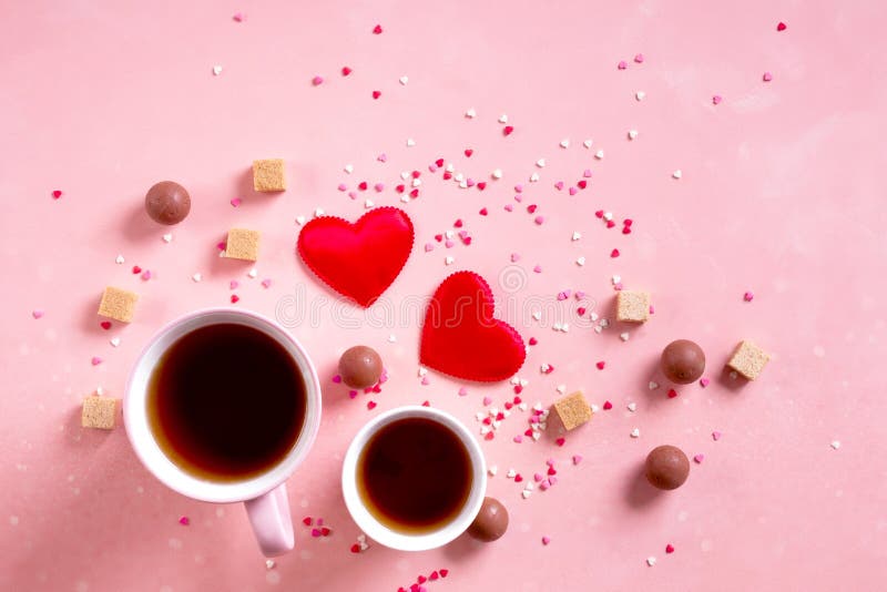 Love drinks. Coffee tea cups for two, sweets candy chocolate on pink hearts background. Valentines day 14 february