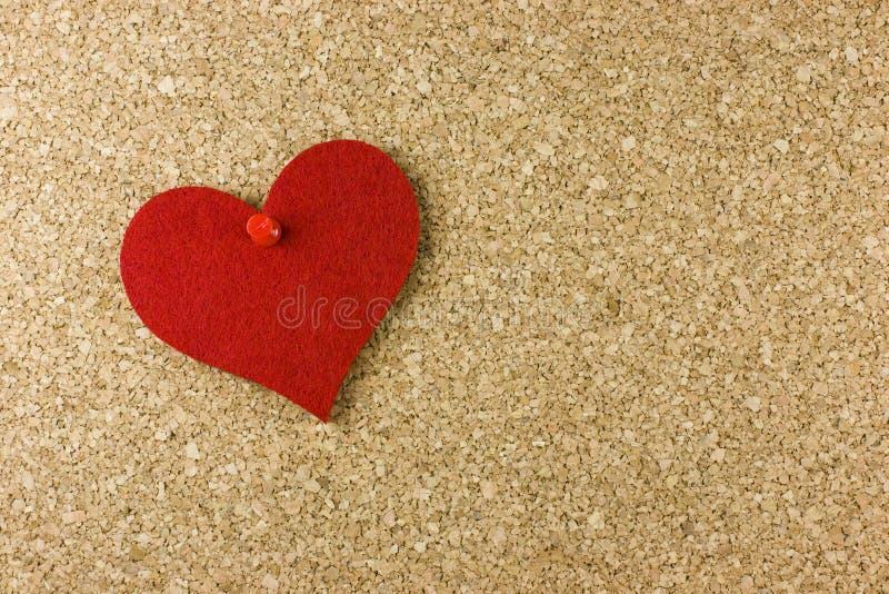 Valentine theme - a red heart attached to a cork board with a red pin. Valentine theme - a red heart attached to a cork board with a red pin.