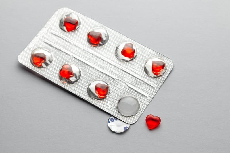 Love pills. Blister pack with red heart shaped pills. Tablets for lovers or potency. Gray background