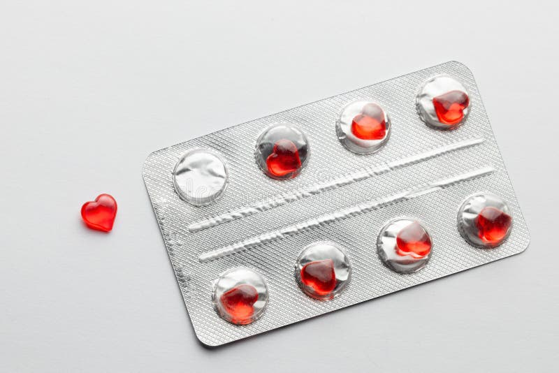 Love pills. Blister pack with red heart shaped pills. Tablets for lovers or potency. Gray background