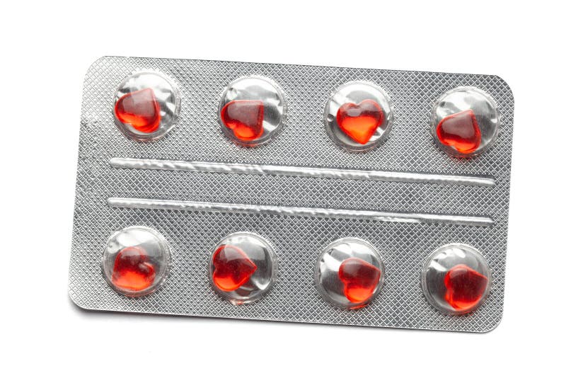 Love pills. Blister pack with red heart shaped pills. Tablets for lovers or potency. Isolated on white