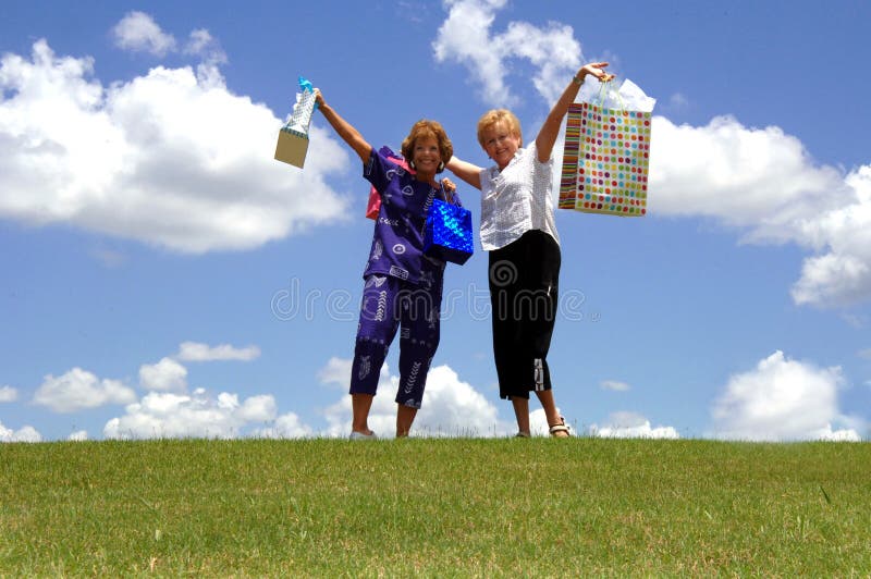 Two happy senior women holding up shopping bags outdoors. Two happy senior women holding up shopping bags outdoors