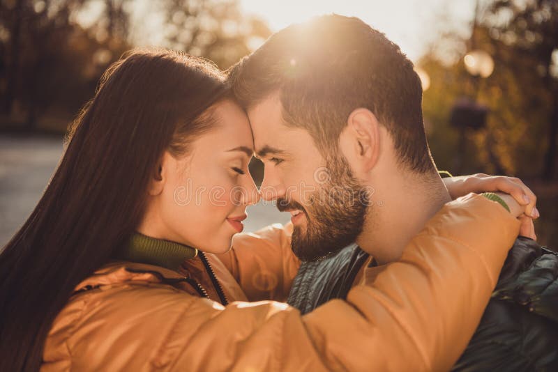 Love soulmate story concept. Passionate bonding couple girl hug guy in autumn town park wear yellow coats