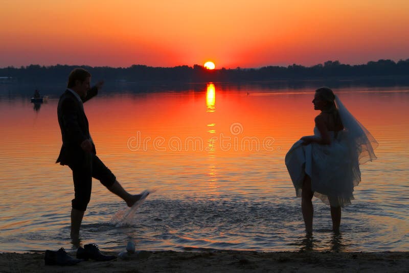 La giovane coppia è in piedi dopo la cerimonia di matrimonio sulla spiaggia e coccole.