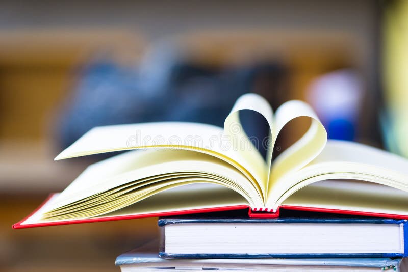 Love to reading books concept : Stack of books and open book heart shape on the table. Library, education, back to school concept.