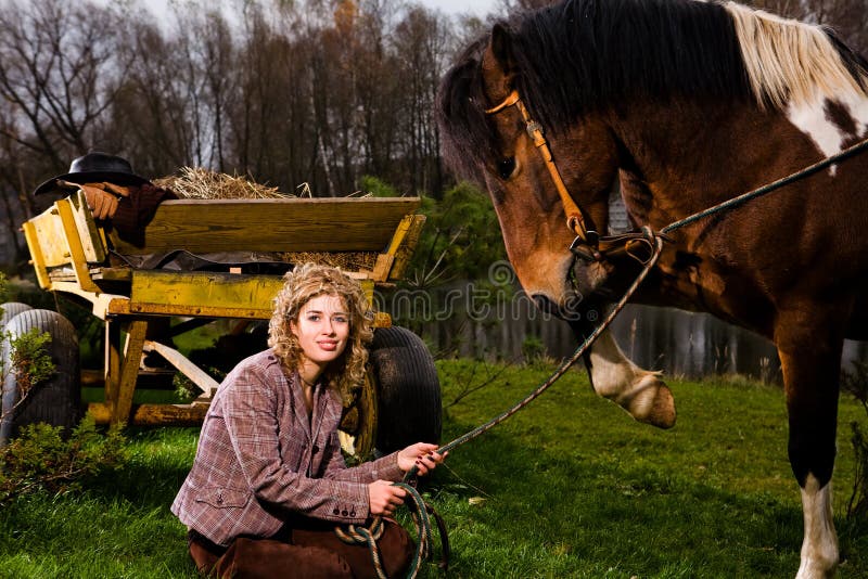 Lovely blond woman sitting by horse