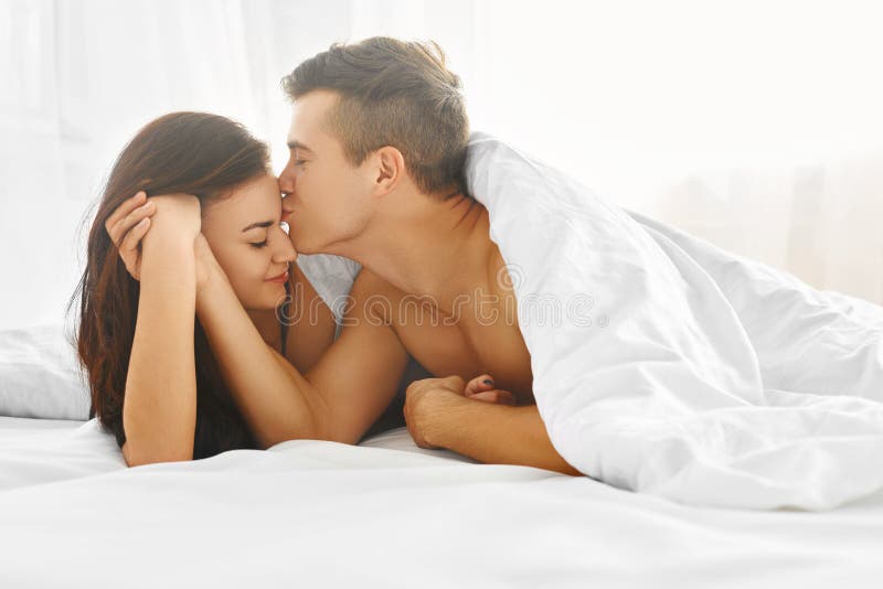 Young lovely tender couple enjoying morning lying in bed in their bedroom. Love and relationships concept. Young lovely tender couple enjoying morning lying in bed in their bedroom. Love and relationships concept.