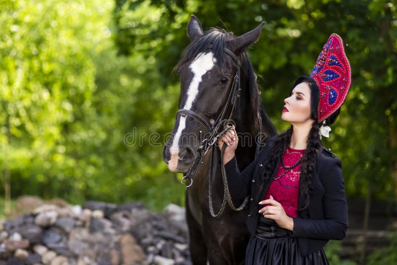 Lovely Fashion Model in Russian Style Kokoshnik Holding Thoroughbred Horse Closely.Posing Against Nature Background. Horizontal Image royalty free stock photos Lovely Fashion Model in Russian Style Kokoshnik Holding Thoroughbred Horse Closely.Posing Against Nature Background. Horizontal Image royalty free stock photos