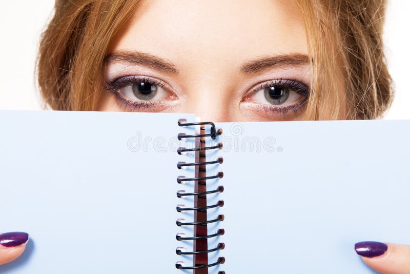 Lovely girl hiding behind notebook