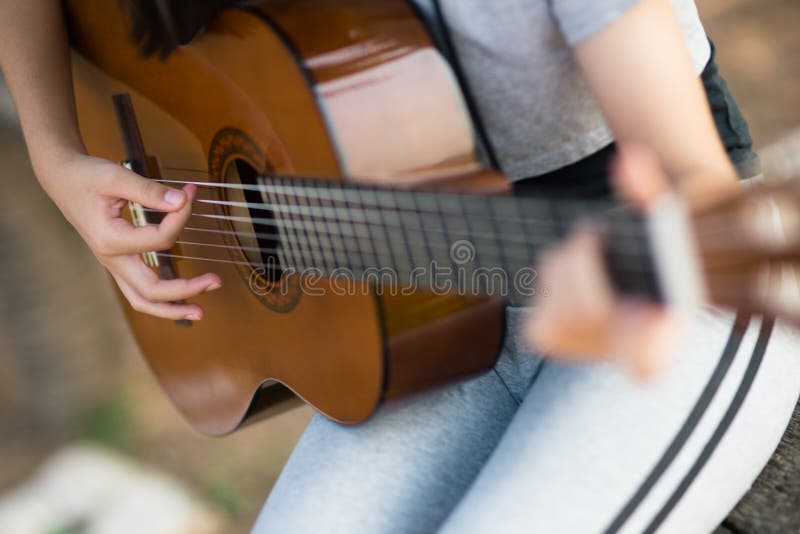 Lovely girl,playing guitar, singing ,music or happiness concept, sunset warm light tone effect.