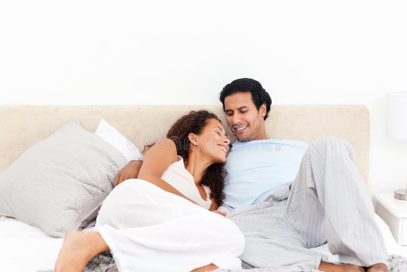 Lovely hispanic couple relaxing in their bedroom during a weekend at home