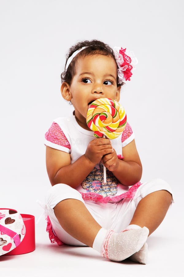 Lovely little girl eating a big lollipop