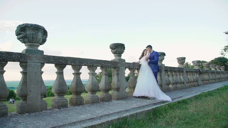 Lovely wedding couple stands in embracess on the castle`s balcony. Slowly stock video footage Lovely wedding couple stands in embracess on the castle`s balcony. Slowly stock video footage