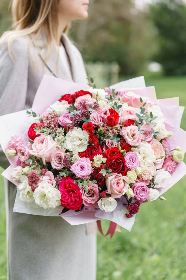 Lovely woman holding a beautiful autumn bouquet. flower arrangement with pink and red color flowers. green lawn on stock photography Lovely woman holding a beautiful autumn bouquet. flower arrangement with pink and red color flowers. green lawn on stock photography