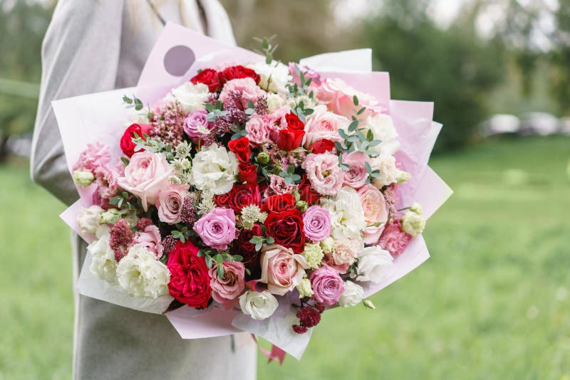 Lovely woman holding a beautiful autumn bouquet. flower arrangement with pink and red color flowers. green lawn on royalty free stock images Lovely woman holding a beautiful autumn bouquet. flower arrangement with pink and red color flowers. green lawn on royalty free stock images
