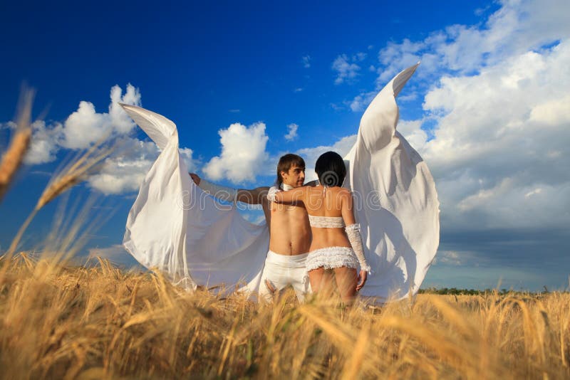 Lovers with white wings on wheat field