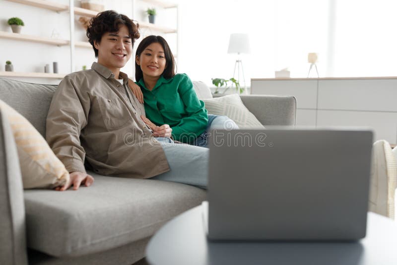 Happy Mixed Race Couple Relax On Couch In Living Room Watch Movie