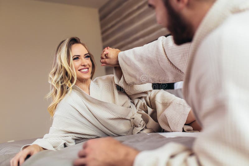 Loving couple in bathrobes relaxing on bed at hotel royalty free stock photography Loving couple in bathrobes relaxing on bed at hotel royalty free stock photography
