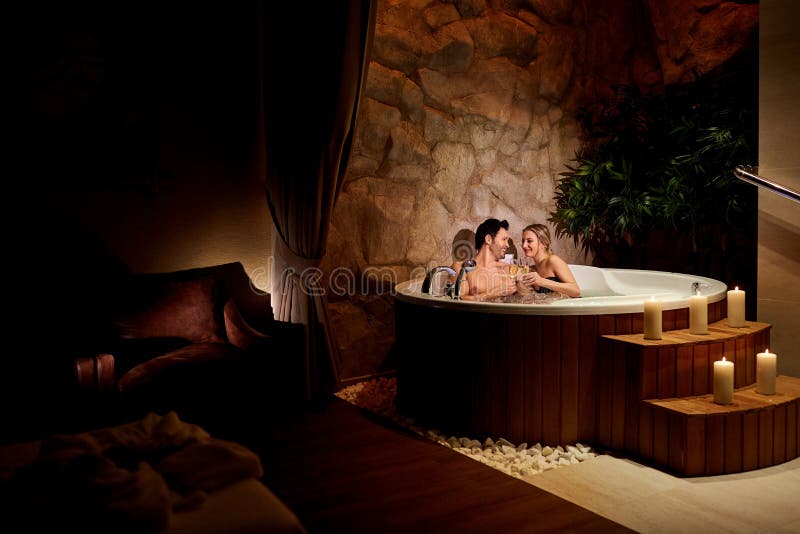 A loving couple with a glass of champagne in a jacuzzi relax. stock photo A loving couple with a glass of champagne in a jacuzzi relax. stock photo