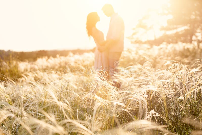 Loving couple kissing at sunset, focus on foreground