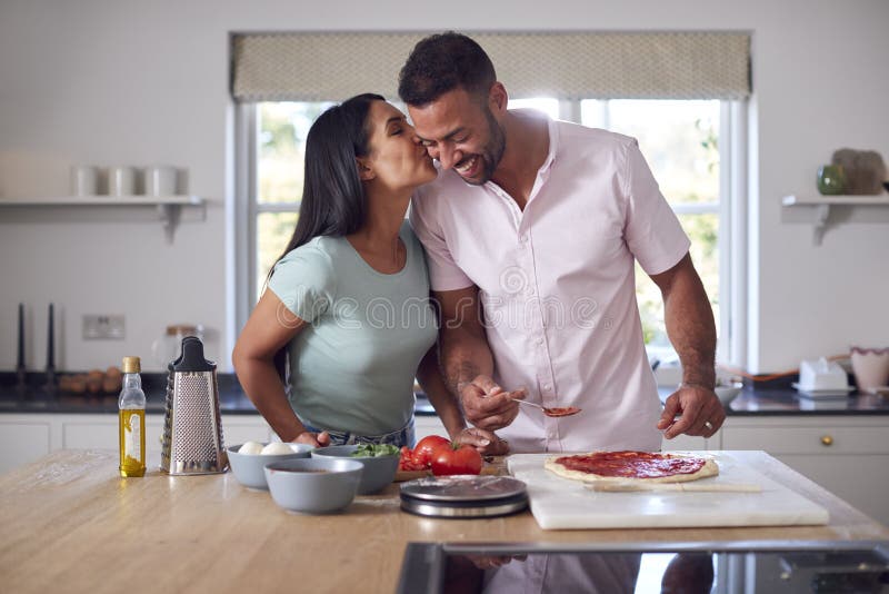 Loving Couple In Kitchen At Home Preparing Homemade Pizzas Together stock photography