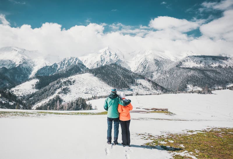 Milující pár stojící a při pohledu na krásné zasněžené vrcholky hor. Panoramatický výhled. Pohled zezadu