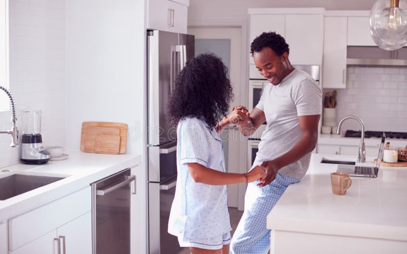 Loving Couple Wearing Pyjamas Having Romantic Dance In Kitchen At Home Together royalty free stock images
