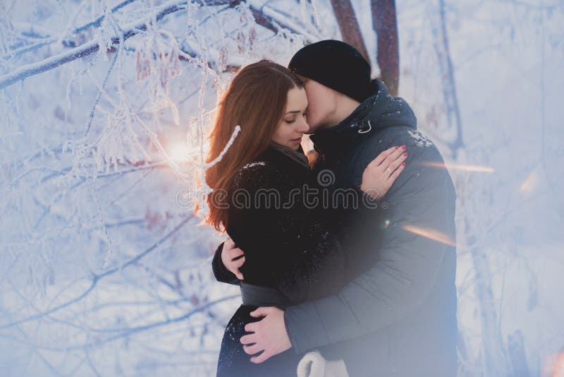 A loving couple on a winter walk. Snow love story, winter magic. Man and woman on the frosty street. The guy and the girl are rest