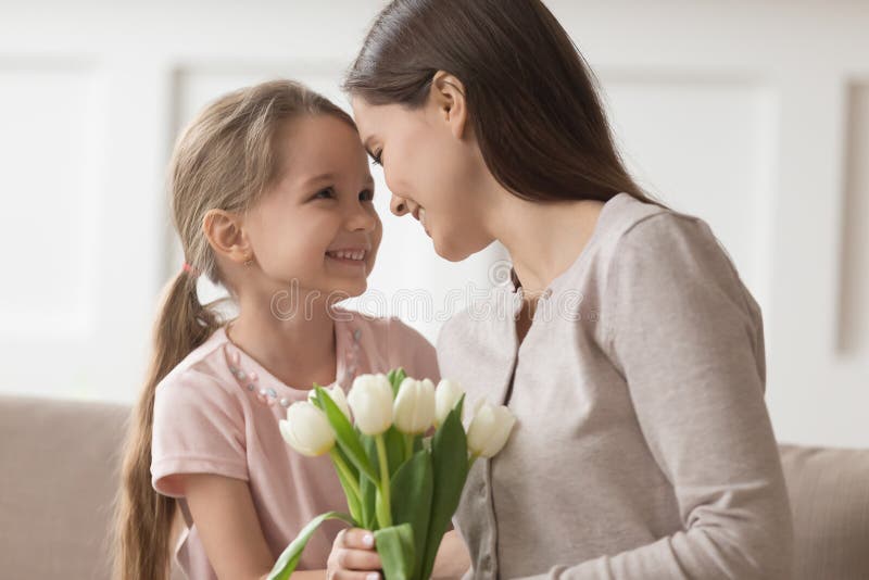 Daughter touch. Give Flowers to mum. Mother is giving a present to daughter.