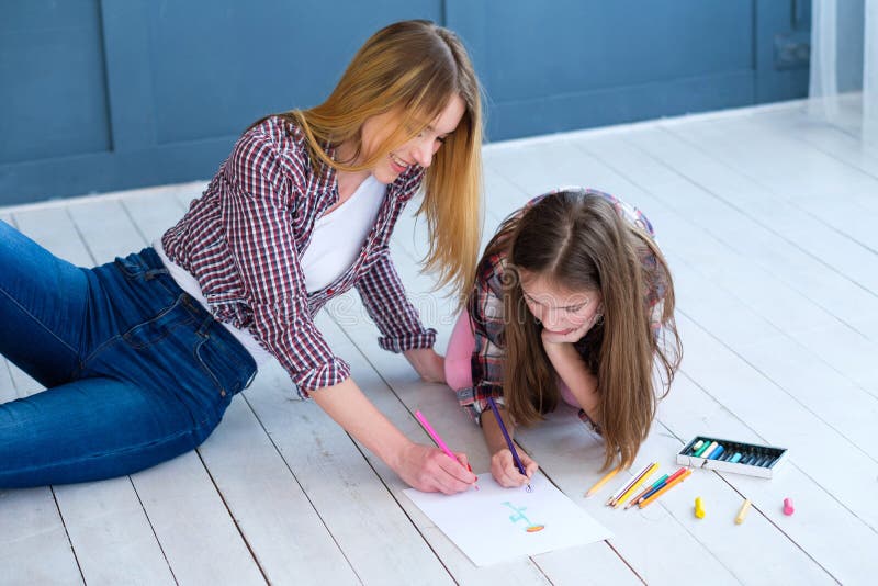 Loving family relationship. mothers involvement in kids hobby. mom and daughter drawing together at home. Loving family relationship. mothers involvement in kids hobby. mom and daughter drawing together at home.
