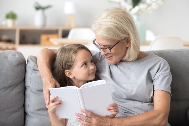 Loving grandmother teaching granddaughter reading book sitting o royalty free stock photo Loving grandmother teaching granddaughter reading book sitting o royalty free stock photo