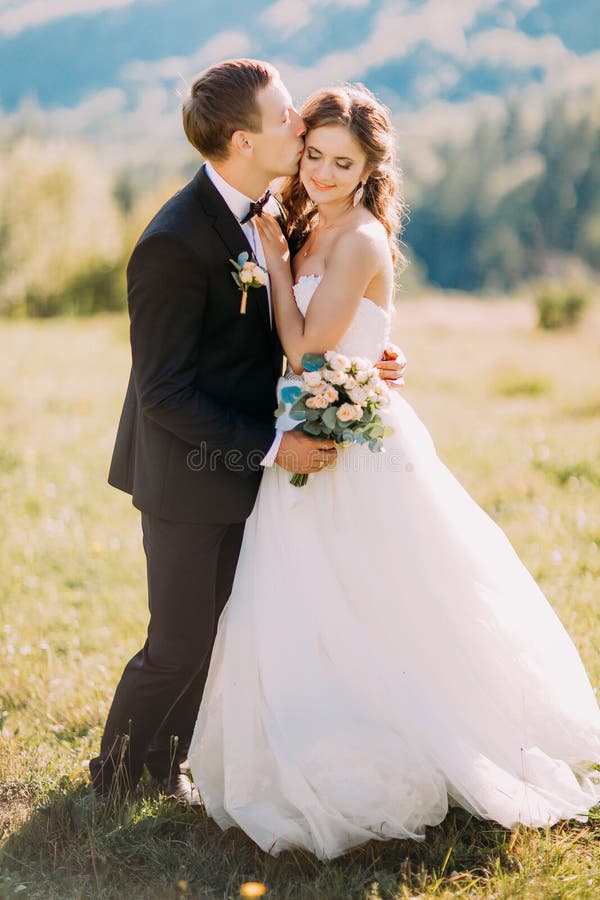 Loving Groom Kissing Bride S Forehead On The Meadow With