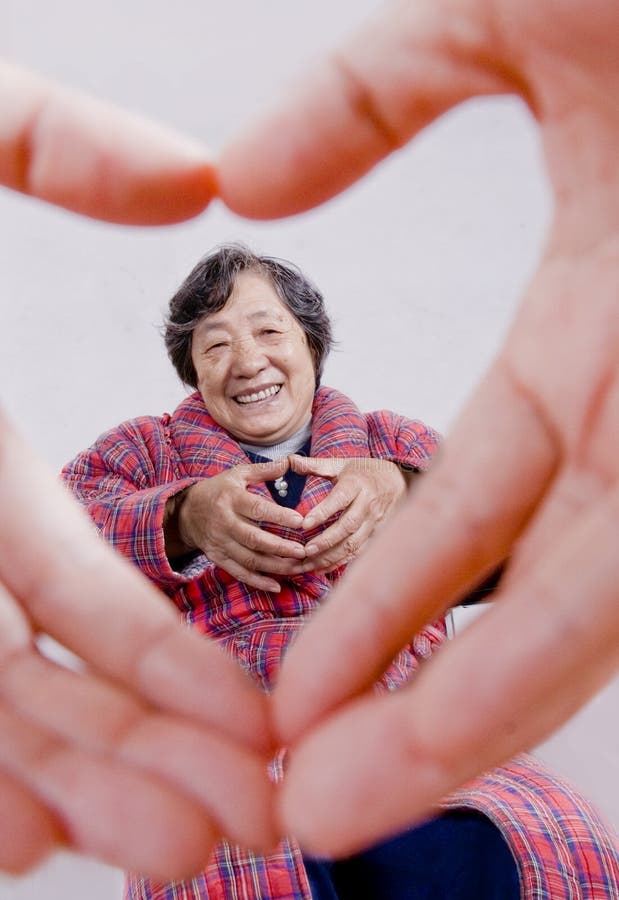 Obrázok smeje čínsky babička s gesto milujúce srdce vidieť z tvare srdca vyrobený ruky.