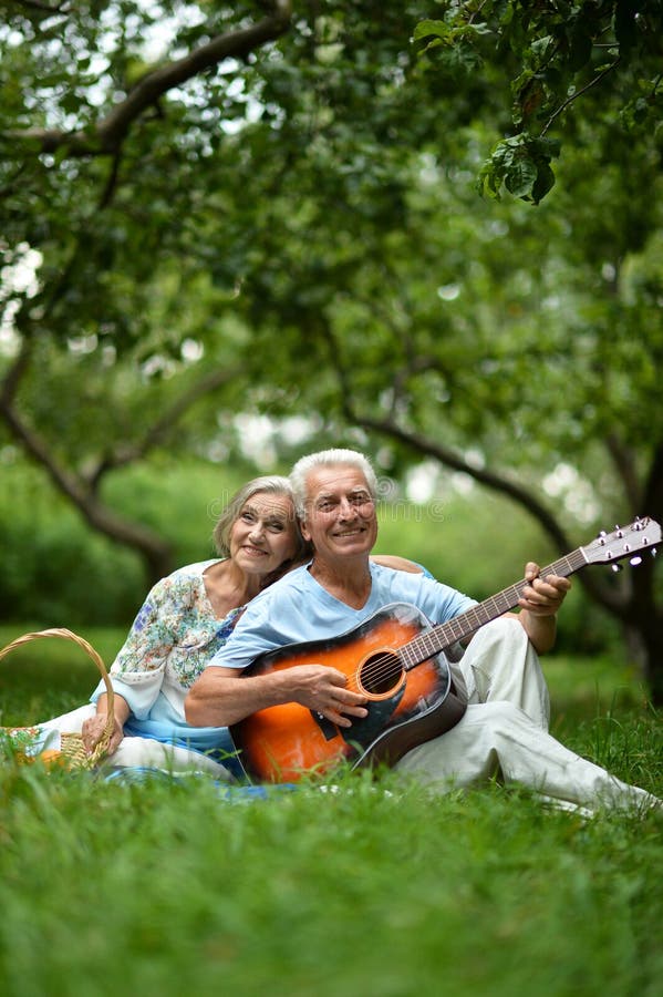 Loving mature couple with guitar in park