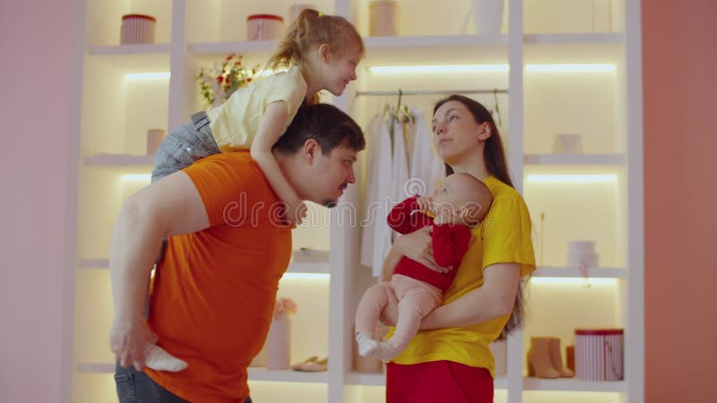 Joyful loving parents with two little daughters bonding and sharing at home