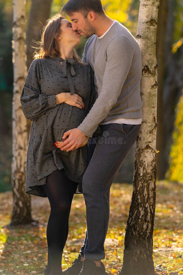 Loving pregnant young couple kissing tenderly.