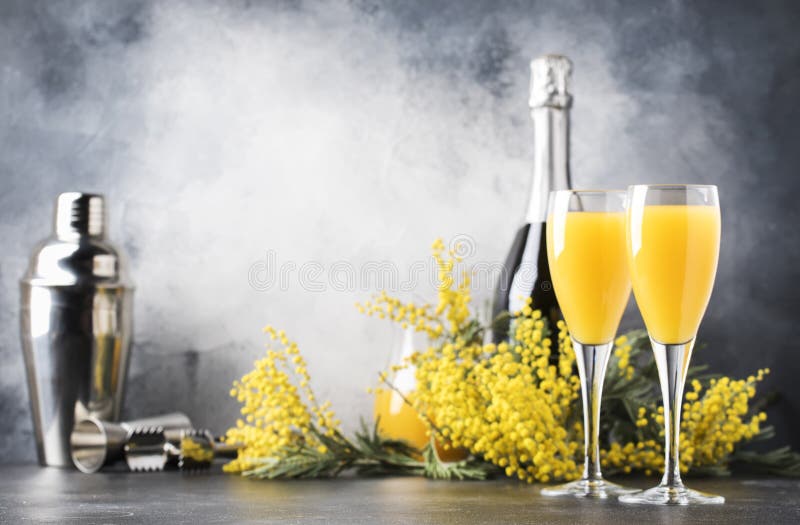 Low alcohol cocktail mimosa with orange juice and cold dry champagne or sparkling wine in glasses, blue background with flowers, place for text, selective focus