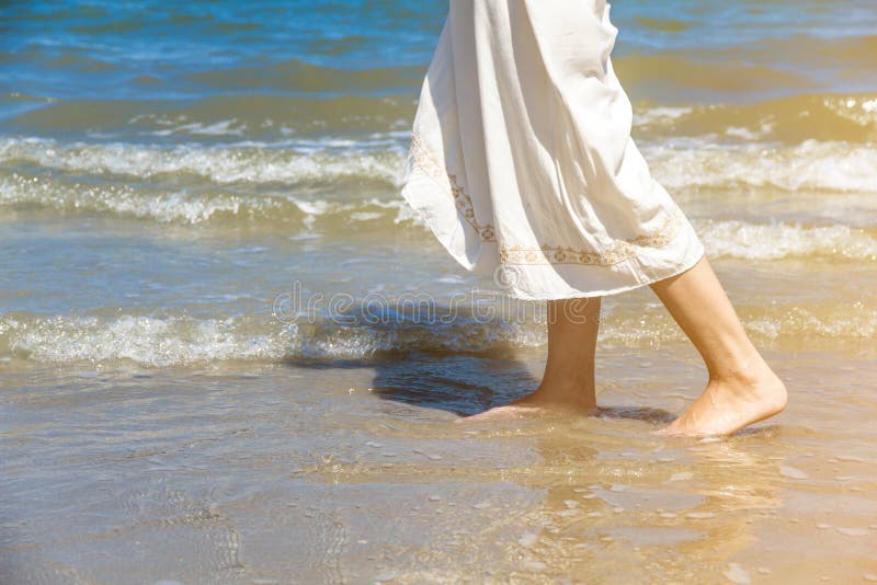 Theâ€‹ Low angle behind woman walking barefoot on beach royalty free stock image