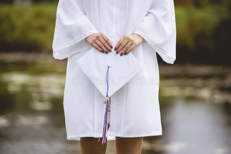 Low angle closeup shot of a female graduate wearing a white cap and gown stock photos Low angle closeup shot of a female graduate wearing a white cap and gown stock photos