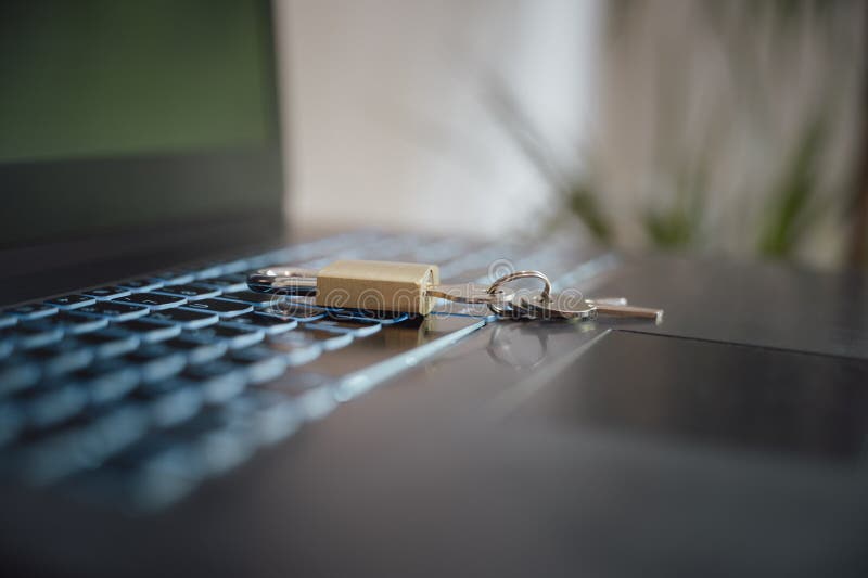 Low angle closeup view of a golden padlock with keys in it placed on laptop computer keyboard royalty free stock photo