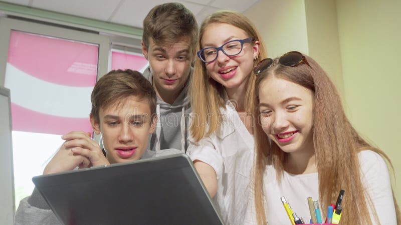 Low angle cropped shot of group of teens studying together, using laptop