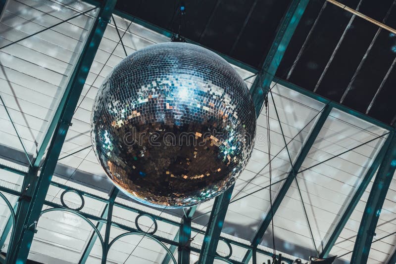 Detailed low angle view of large reflecting disco ball hanging from tall ceiling. Detailed low angle view of large reflecting disco ball hanging from tall ceiling